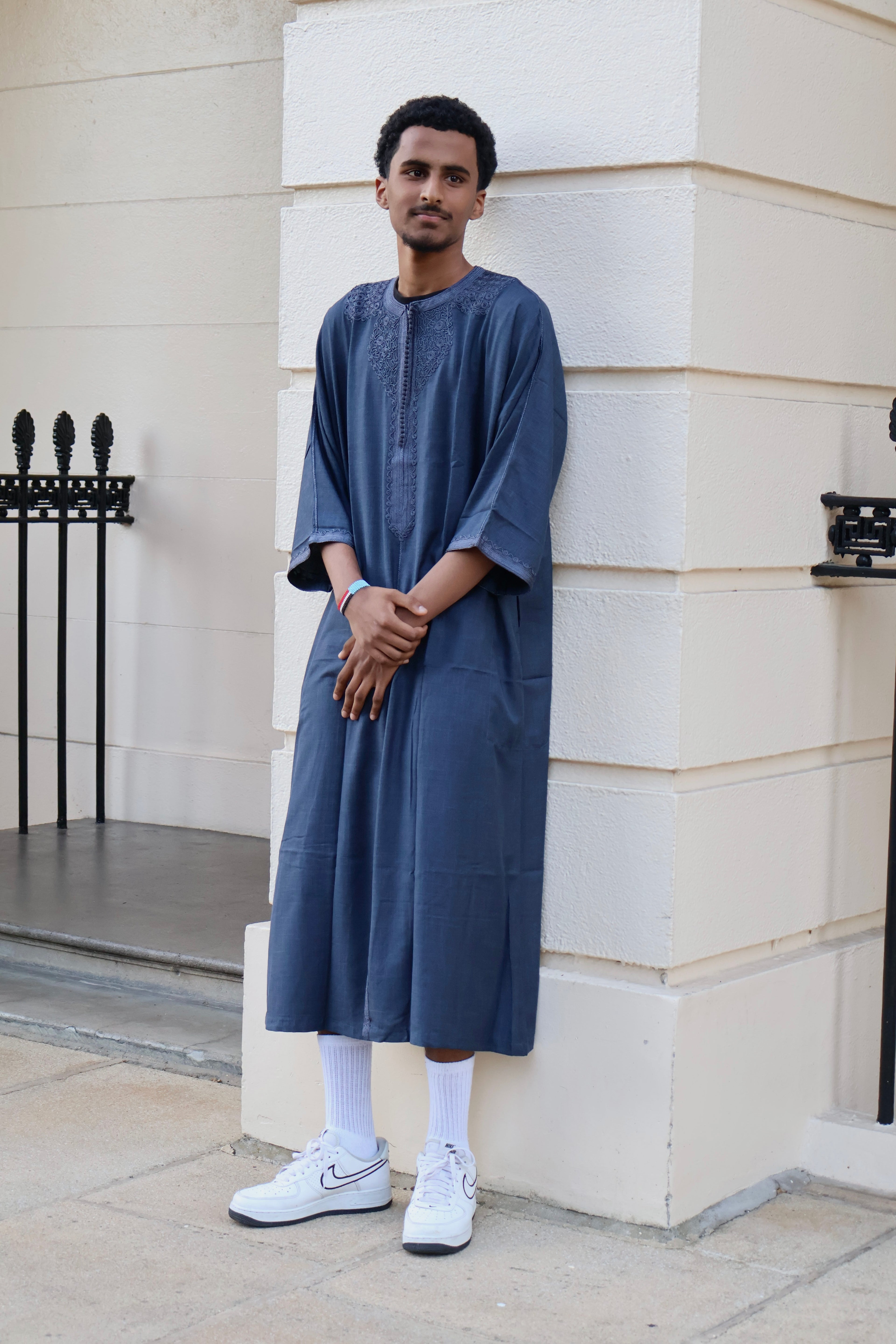 Man leaning against a wall, wearing a men&