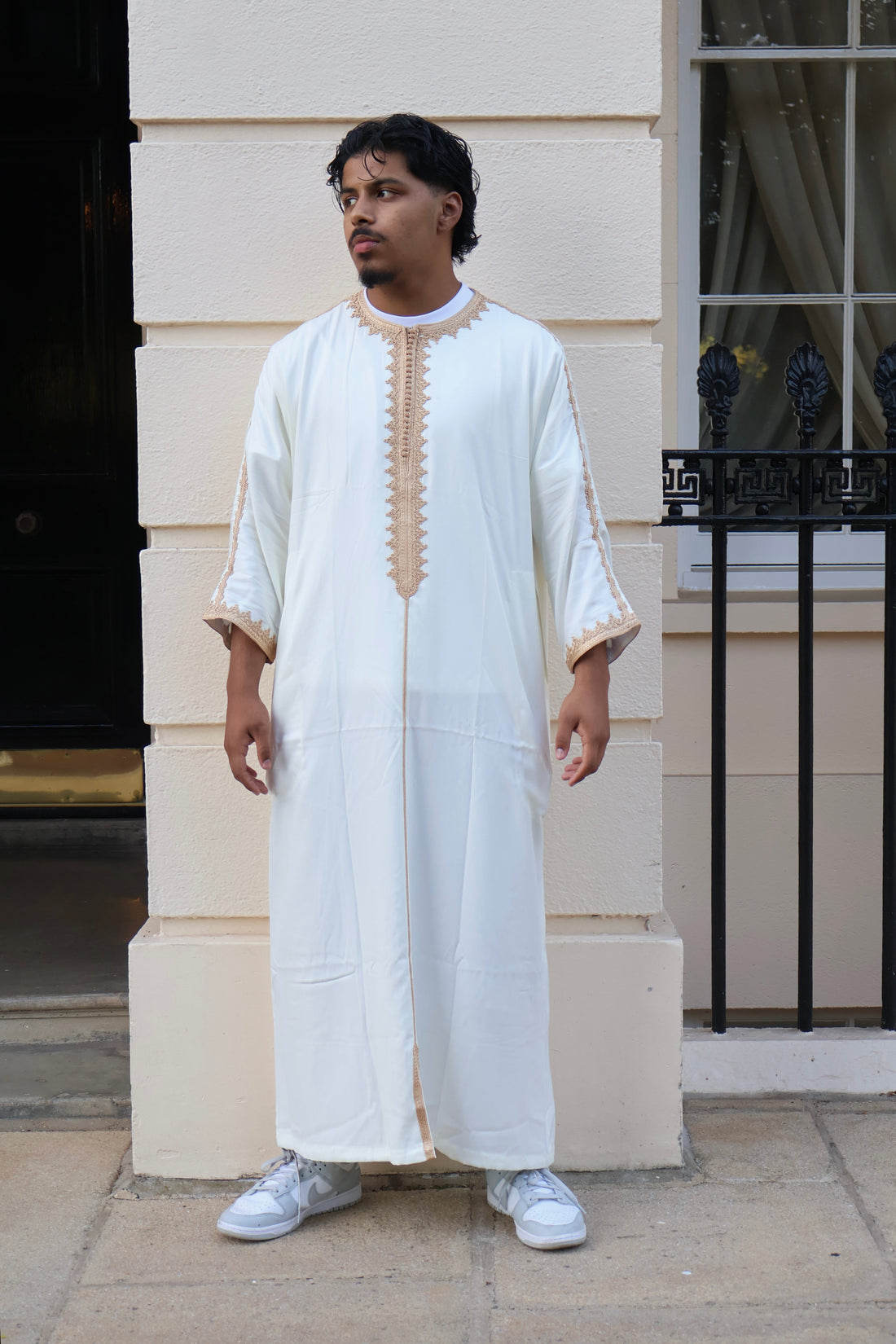 Man standing against a cream wall, wearing a men&