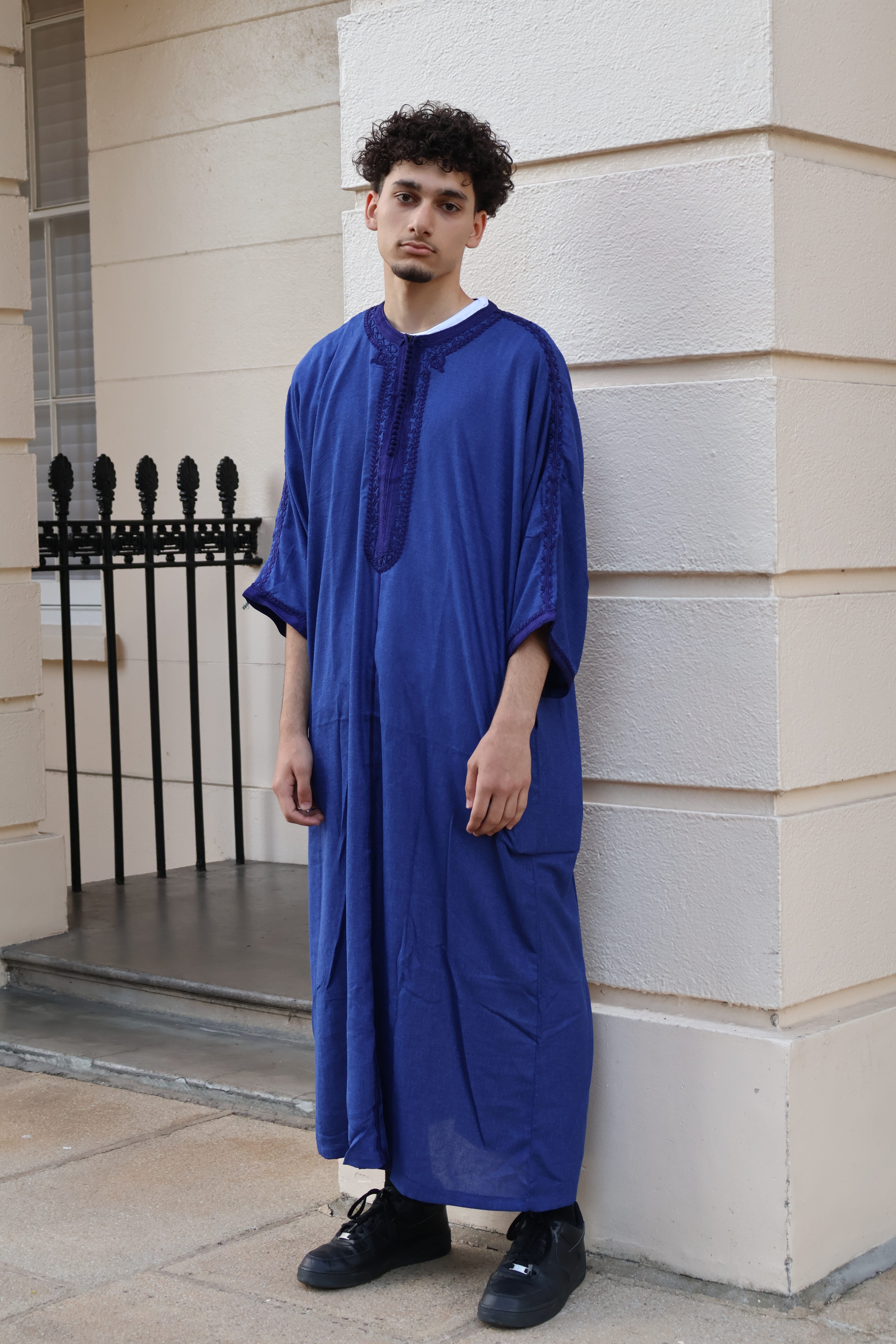 Man standing outdoors in front of a white building, wearing a vibrant royal blue men&