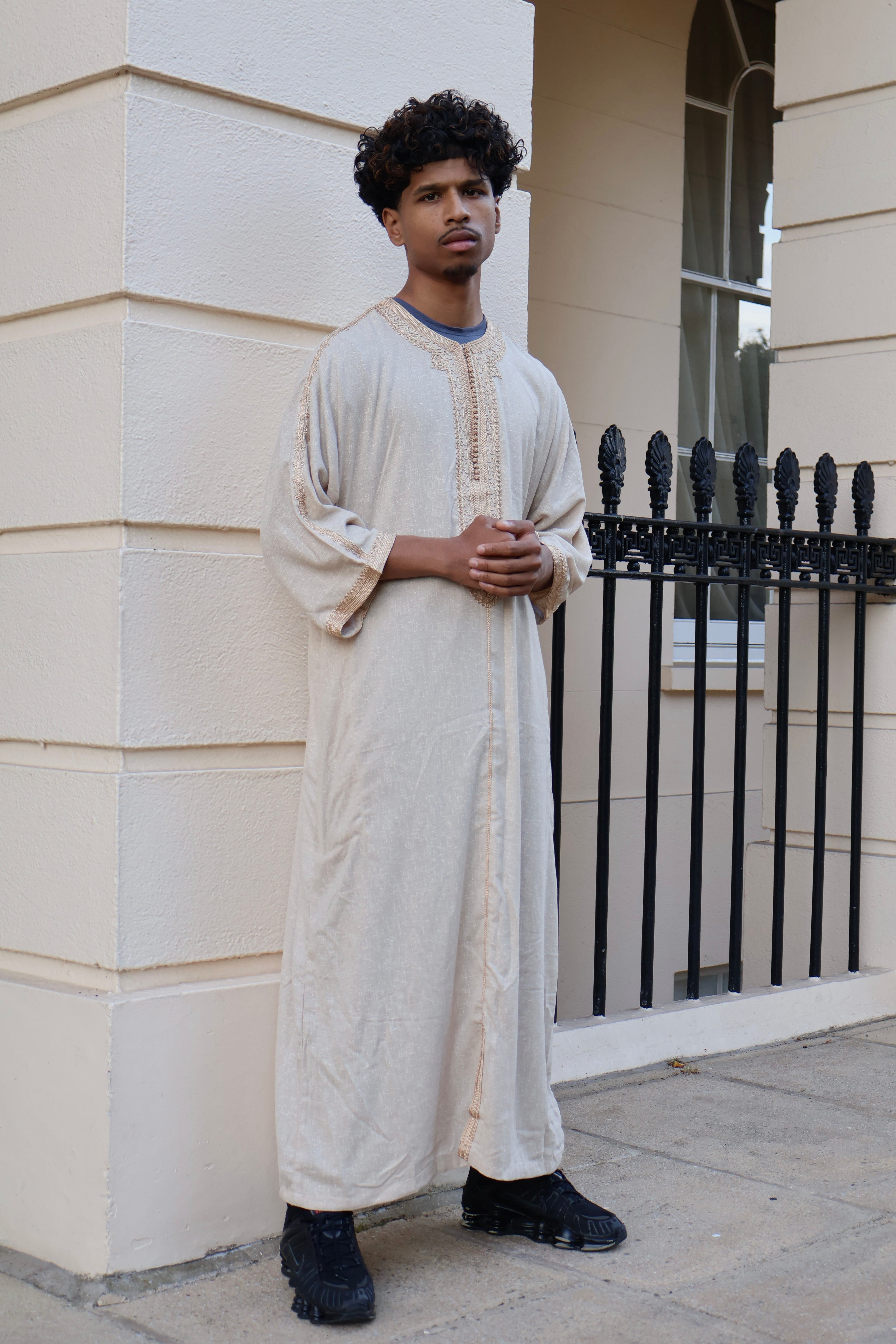 Man standing against a wall, wearing a cream men&