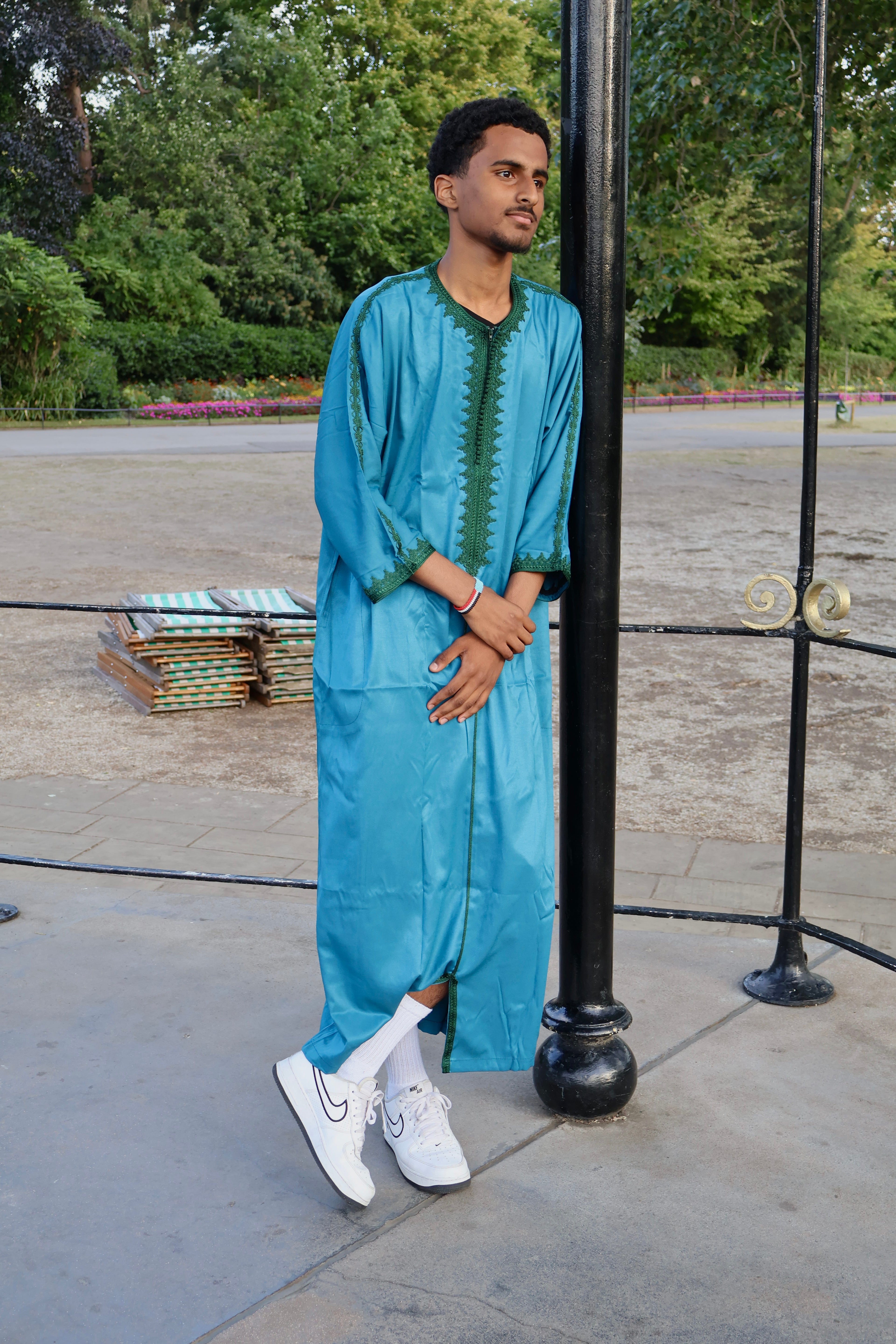 Man leaning on a pole outdoors, wearing a men&