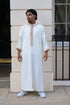 Man standing against a cream wall, wearing a men&