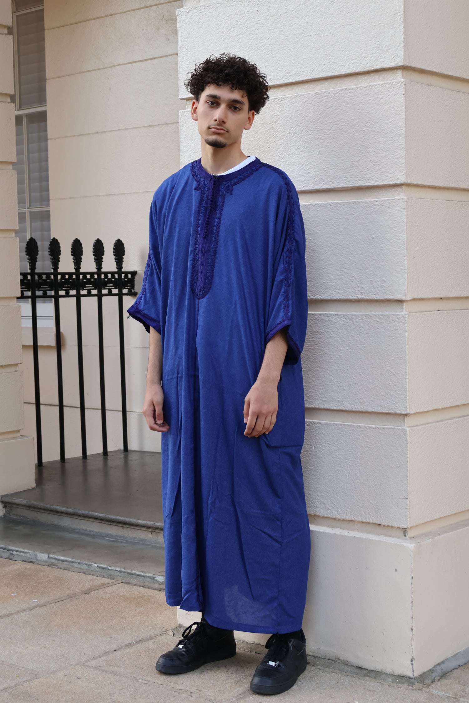 Man standing outdoors in front of a white building, wearing a vibrant royal blue men&