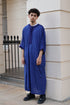 Man standing outdoors in front of a white building, wearing a vibrant royal blue men&