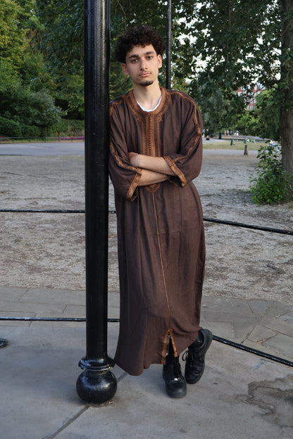 Man with arms crossed, leaning on a pole, wearing a luxurious brown men&